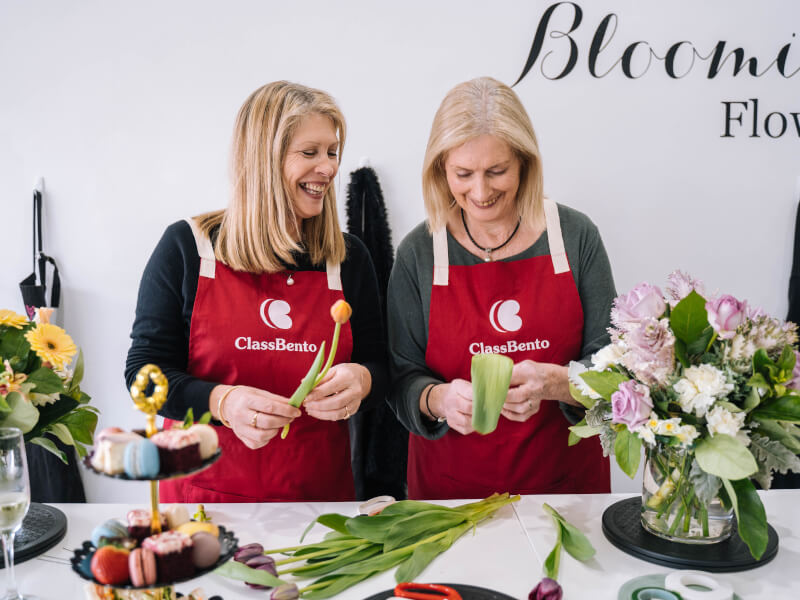 A mother and daughter smile and laugh at a flower arranging class